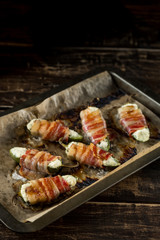 Vegetables stuffed with cheese and bacon and baked on tray in oven. Rustic recipe food on wooden background. Top view