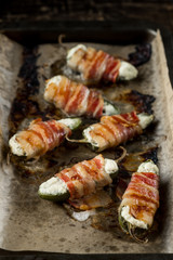 Vegetables stuffed with cheese and bacon and baked on tray in oven. Rustic recipe food on wooden background. Top view