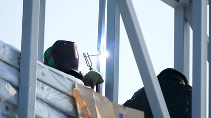 Welder protective mask works outdoors in winter closeup. welder working with electrode at arc welding in construction site winter outdoors. Welder protective mask works outdoors in winter close up.