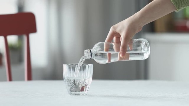 Woman pouring water from bottle to glass