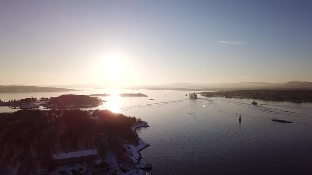 Aerial shot of islands in Oslo fjord towards sun at sunset in winter