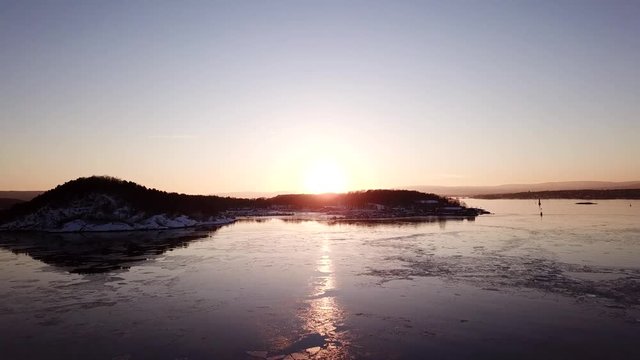 Aerial shot of islands in Oslo fjord towards sun at sunset in winter