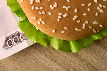 Burger with one hundred russian ruble bill close up