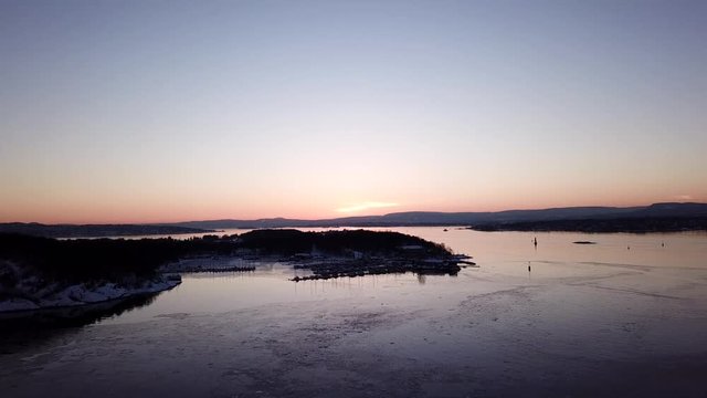 Aerial shot of islands in Oslo fjord towards sun at sunset in winter