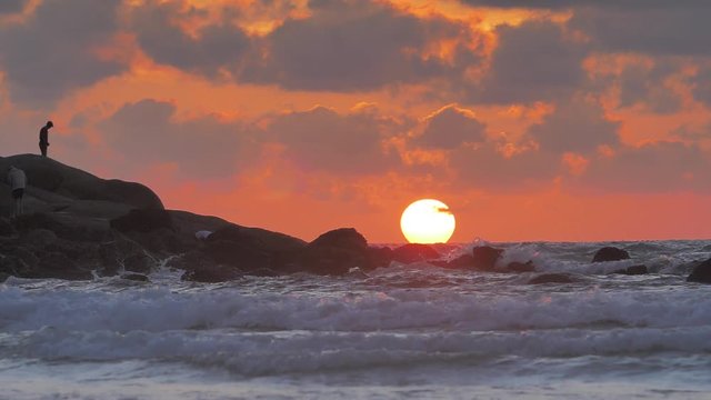 Beautiful Ocean sunset with last light of the Sun in sea waves crashing against rocks in slowmotion
