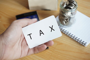 person hand holding card with tax word