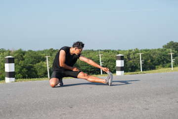 Naklejka premium Male runners are stretching the leg muscles to prepare for a run in the morning. The concept of health and fitness