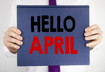 Writing text showing Hello April. Business concept for Spring Welcome written on book notebook paper holding by the man in suit blurred background.