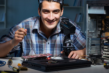 Repairman trying to repair laptop with miscroscope