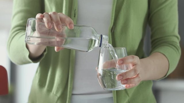 Woman pouring water from bottle to glass