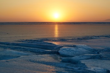 Winter sunset over frozen bay.