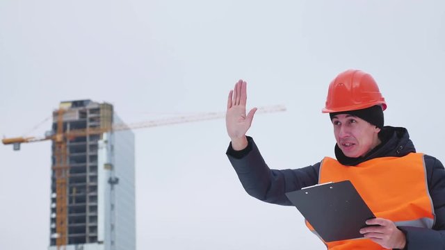 Worker on a construction site in winter directs and hand gesticulating.