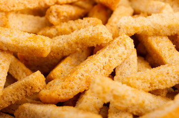 Ruddy golden wheat croutons sticks closeup with blur as background.