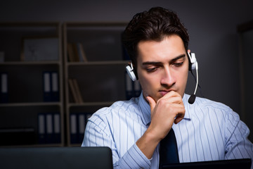 Call center operator talking to customer during night shift 
