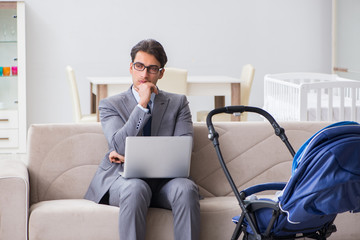 Businessman looking after newborn baby at home and teleworking