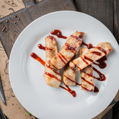 Gourmet main dish with grilled pork rib on white plate. Served on wooden table. Flat lay, top view.