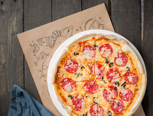 Italian Pepperoni pizza with salami on dark wooden background.  Italian traditional food. Popular street food. Flat lay, top view.