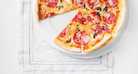 Italian Pepperoni pizza with salami on white wooden background. Italian traditional food. Popular street food. Flat lay, top view. 