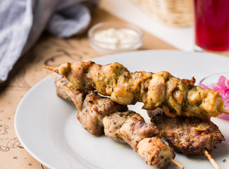 Assorted delicious grilled meat with sauces on white plate. BBQ plate with different kinds of meat. Street fast food.