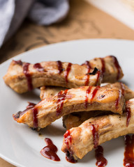 Gourmet main dish with grilled pork rib on white plate. Served on wooden table. Flat lay, top view.