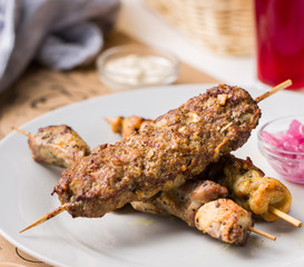 Assorted delicious grilled meat with sauces on white plate. BBQ plate with different kinds of meat. Street fast food.