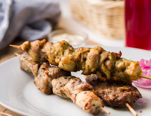 Assorted delicious grilled meat with sauces on white plate. BBQ plate with different kinds of meat. Street fast food.