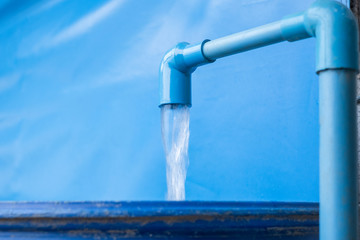 Blue pvc pipe with flowing water in bucket