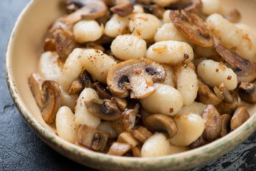 Close-up of potato gnocchi with fried champignons and onion, selective focus