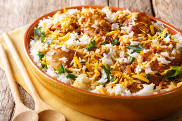 Indian pilaf biryani with chicken, onion, lemon, spices and cilantro close-up. horizontal