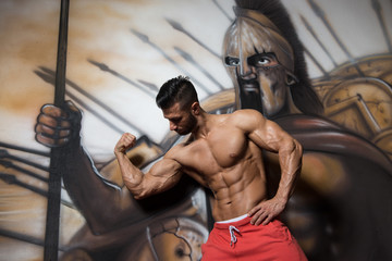 Muscular Man Flexing Muscles At Graffiti Wall