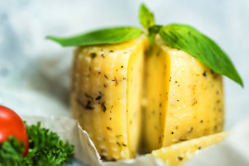 Rustic cheese with herbs on paper and tomatoes
