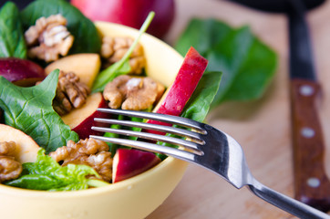 Spinach salad with nuts and apples served on table