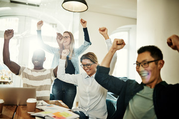 Ecstatic group of diverse coworkers cheering together in an office