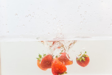 Red strawberry splashing in clear water