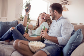 Couple watching TV and eating popcorn.