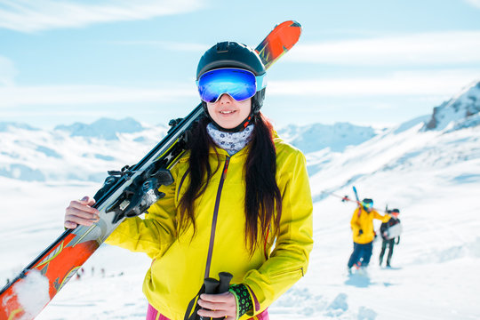 Image of girl looking at camera wearing helmet, mask with skis