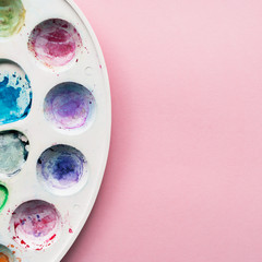 Watercolor palette on a pale pink pastel background. Place for your design, text, etc.