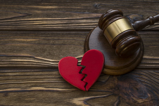 figure of a broken red heart, gavel, hammer of a judge on a wooden background. Divorce proceedings, the dissolution of marriage. court, law.