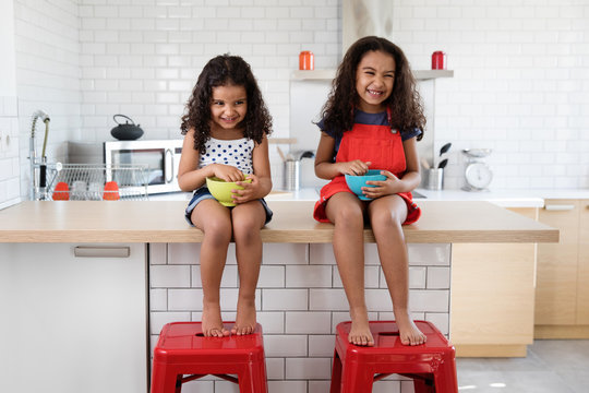 happy little girls sitting on kitchen counter having breakfast