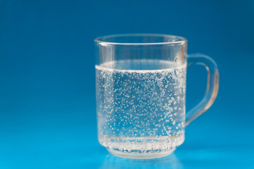 Glass cup with bubbles of air on blue background. Selective focus wtih shallow depth of field.
