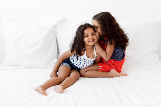 Little girls smiling and sharing secrets on bed