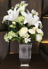 Bunch of flowers arrangement for household decoration in a vase on wooden cupboard