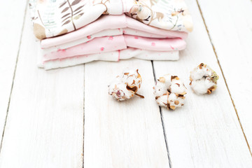 Fototapeta premium Baby clothes from organic cotton and cotton flower on wooden background. Flat lay
