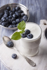 Yogurt with fresh blueberries in a glass on a white cutting board