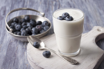 Yogurt with fresh blueberries in a glass on a white cutting board