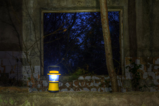 Luminous hand lantern standing on the dilapidated wall of the abandoned restaurant on the top of Mount Akhun at night, Sochi, Russia

