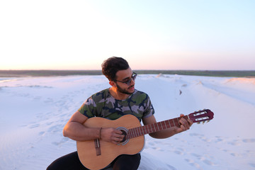 Handsome guy, Arab playing with pleasure on musical stringed instrument and with beautiful smile on...