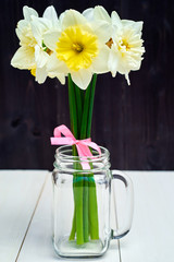 Bouquet of daffodil flowers in glass jar on wooden background, copy space. Top view, flat lay. White narcissus. Spring flowers. Greeting card for March 8 (Womens Day), Mothers day, Easter