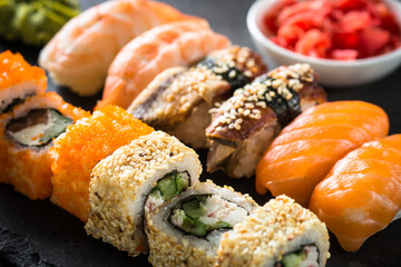 Sushi and sushi roll set on black stone table.