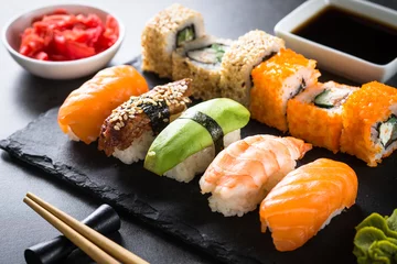 Rolgordijnen Sushi en sushi roll ingesteld op zwarte stenen tafel. © nadianb